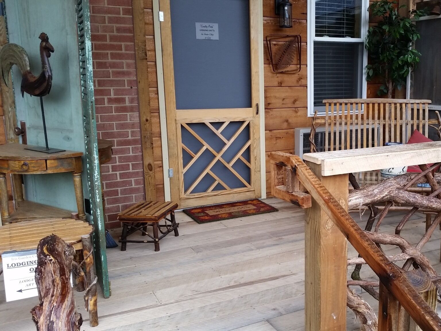 A rustic wooden entrance with a decorative rooster, a wooden bench, and a sign indicating lodging services.
