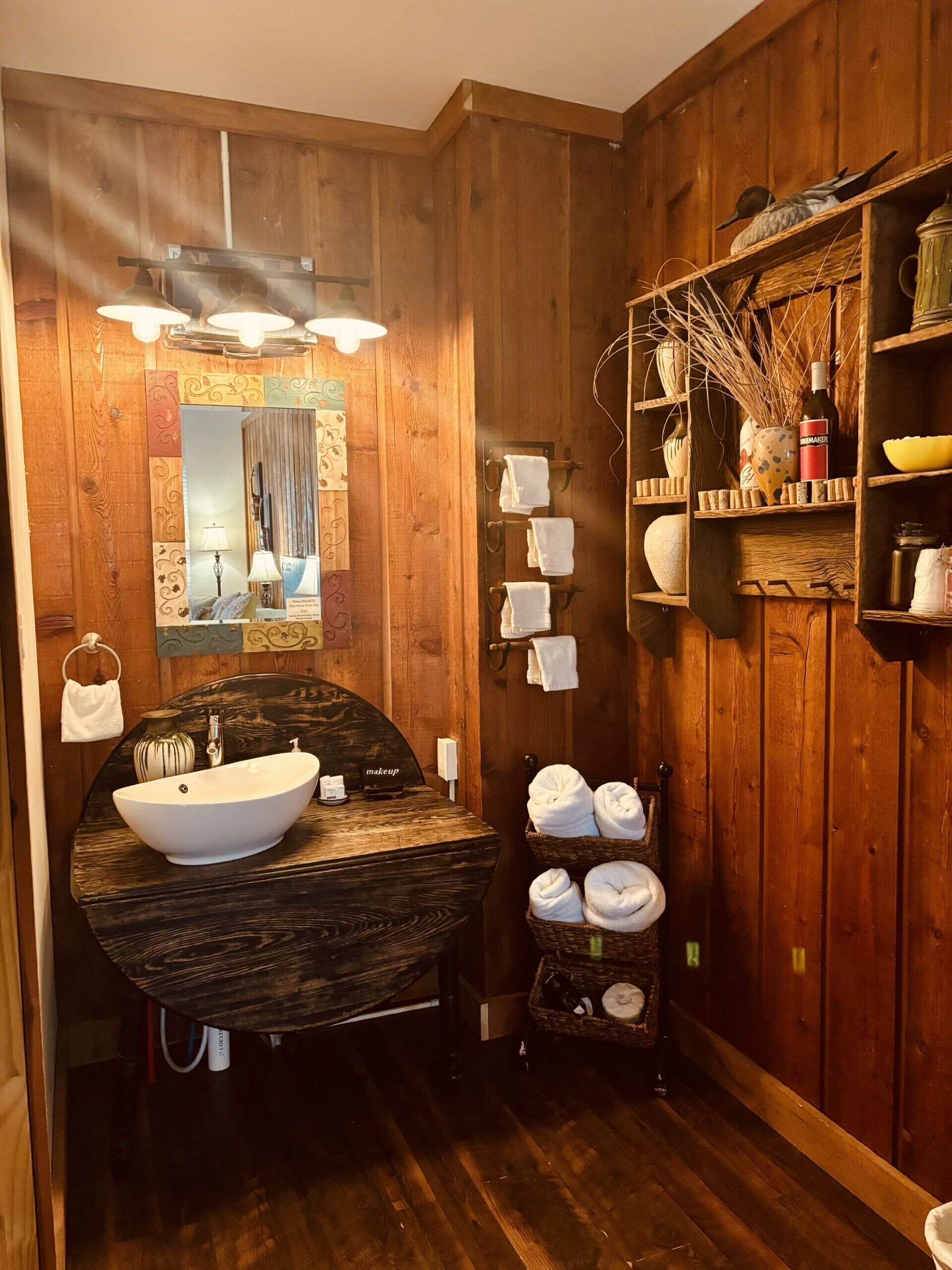 A wooden bathroom with a large mirror, a sink, and a towel rack.