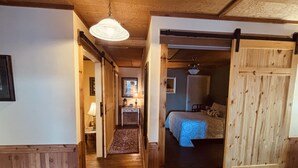 Un couloir en bois mène à une chambre à coucher qui contient un lit et une armoire.