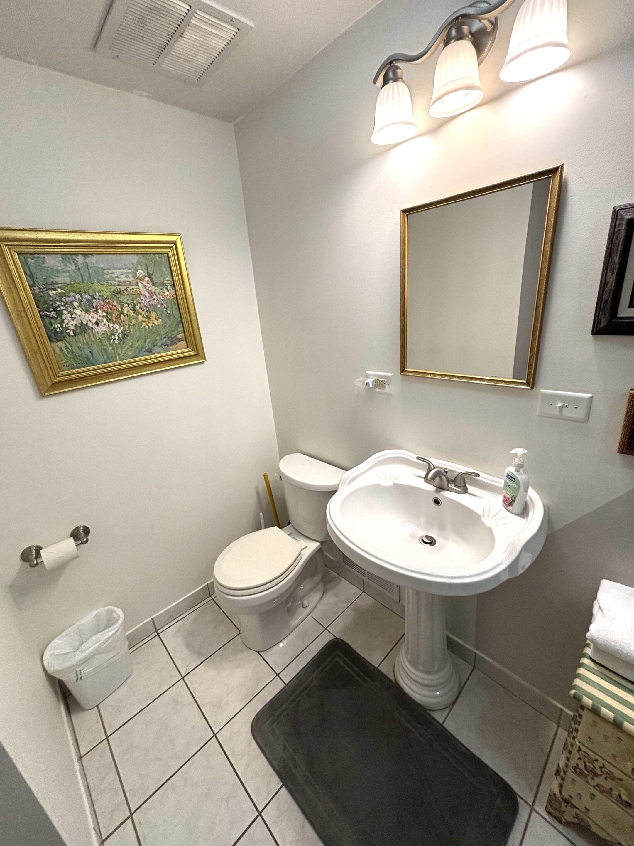Une salle de bain avec des toilettes, un lavabo et un tableau encadré au mur.