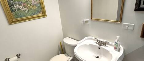 Ein Badezimmer mit Toilette, Waschbecken und einem gerahmten Bild an der Wand.