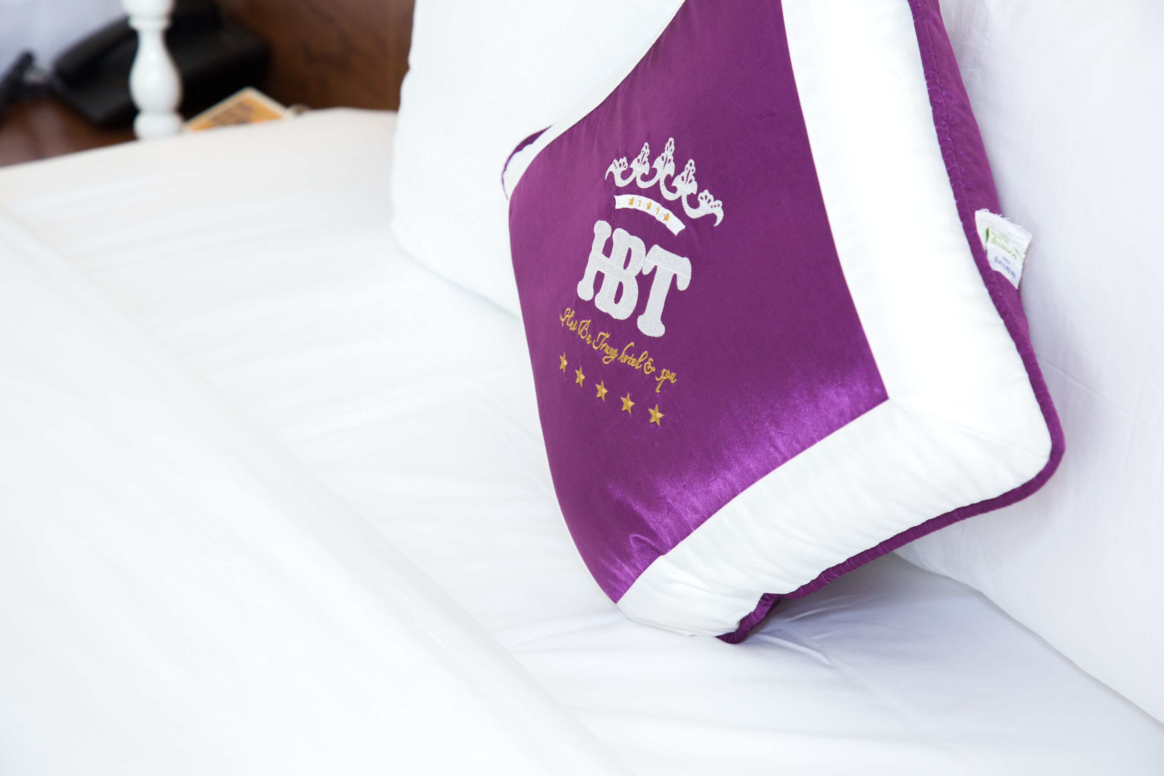 A bed with a white mattress and a purple pillow with "HT" and "I'm the best friend to you" text.