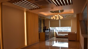 A modern lobby with a reception desk, seating area, and a large window providing a view. - Hotel Deep Clarks Inn Lucknow  (Lucknow)