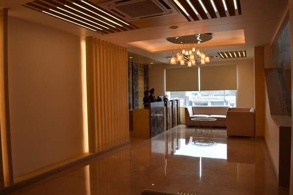 Um hall moderno com balcão de recepção, área de estar e uma grande janela com vista.