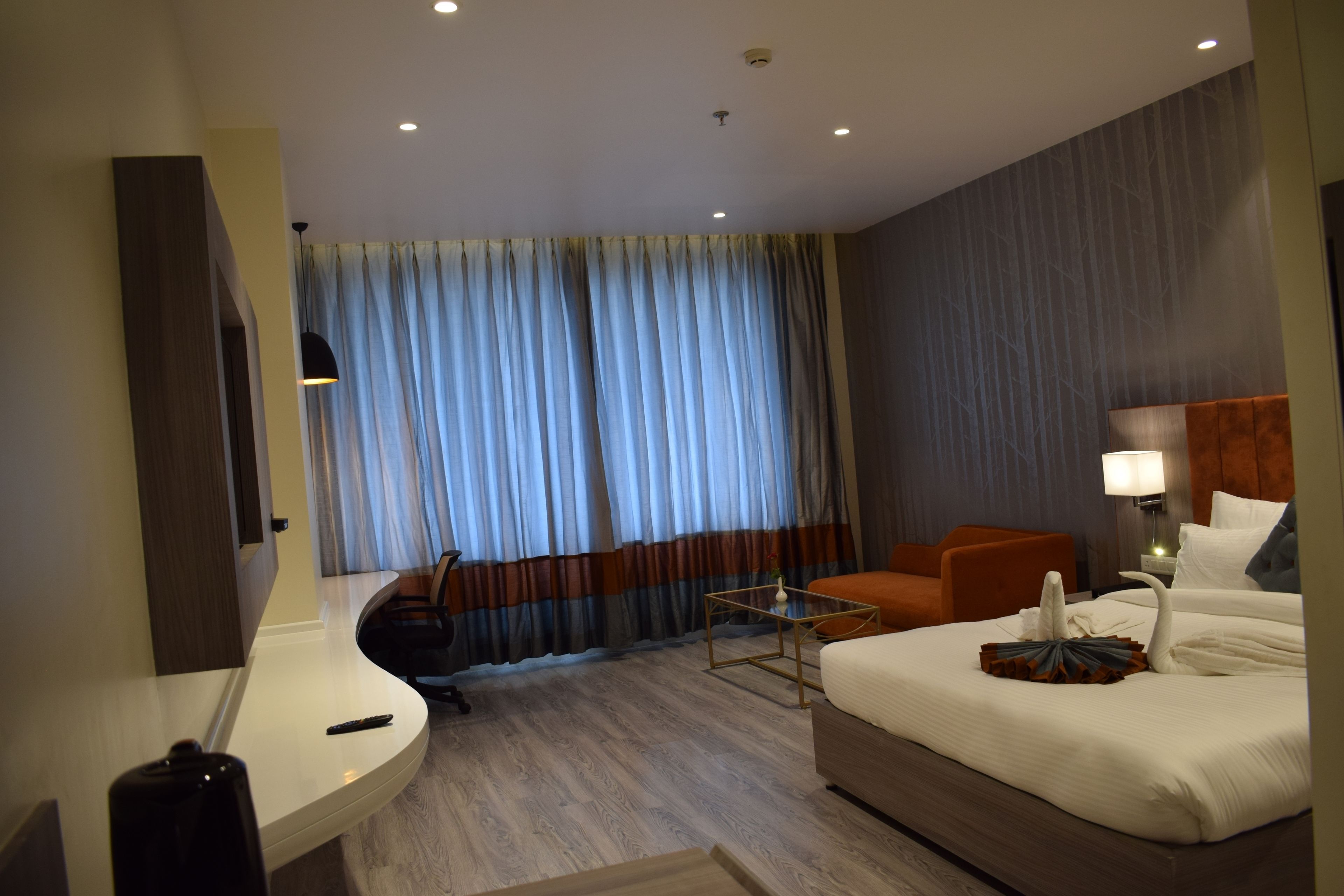 Ein Hotelzimmer mit Bett, Schreibtisch, Stuhl, kleinem Tisch und Fernseher.