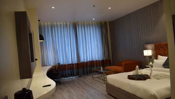 Ein Hotelzimmer mit Bett, Schreibtisch, Stuhl, kleinem Tisch und Fernseher.