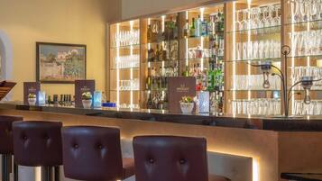 A bar area with a counter, bar stools, and shelves stocked with bottles and glasses.