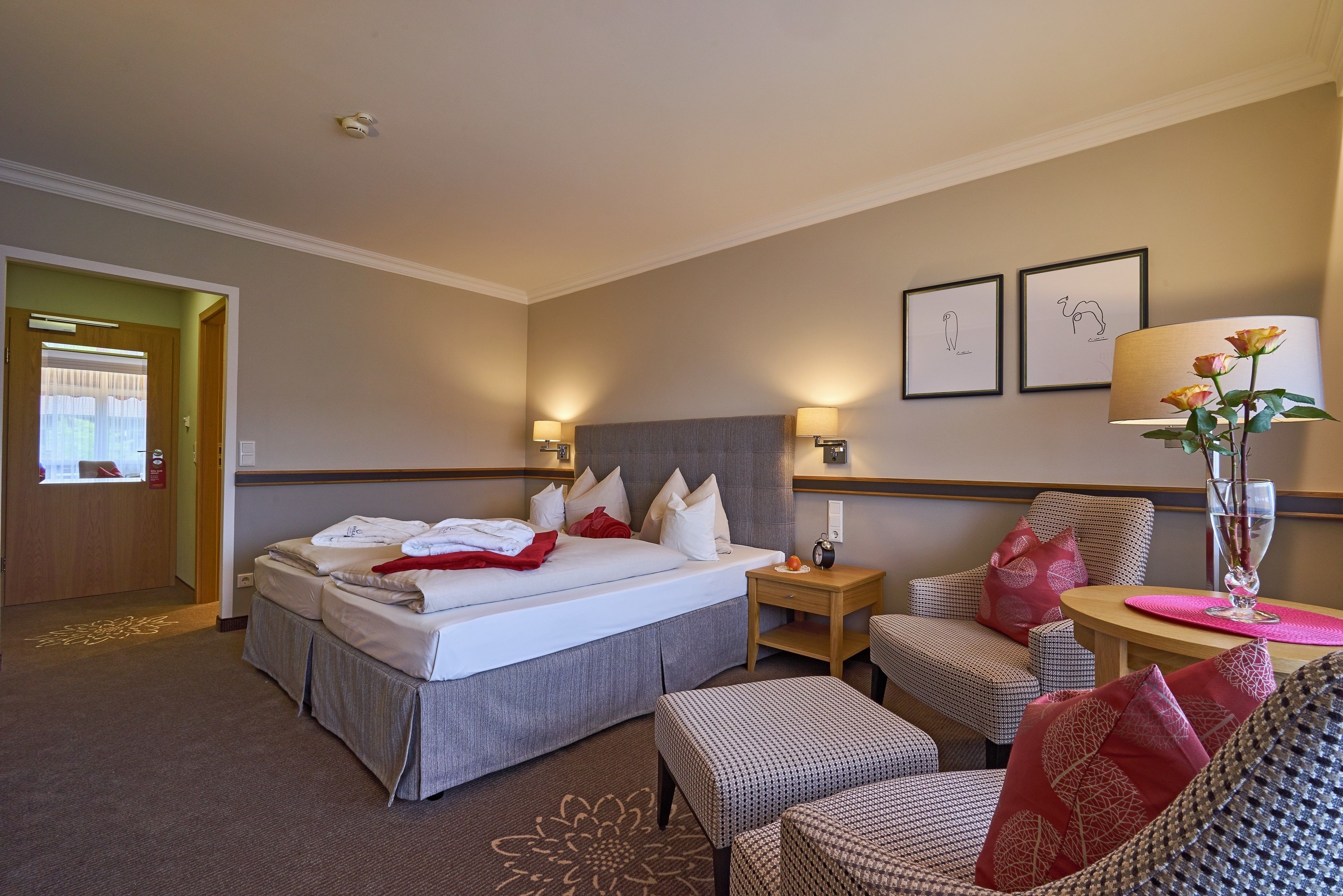 Ein Hotelzimmer mit einem Bett, zwei Nachttischen, einem Sessel, einem kleinen Tisch und einer Dekorationsvase.