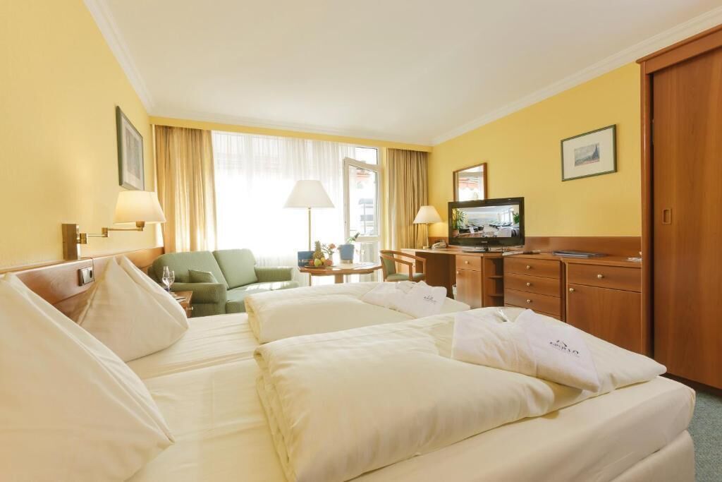 A hotel room with two beds, a television, a desk, and a chair.