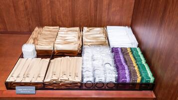 A display of various packaged items, likely toiletries, arranged on a wooden counter with a sign instructing to take one for free.