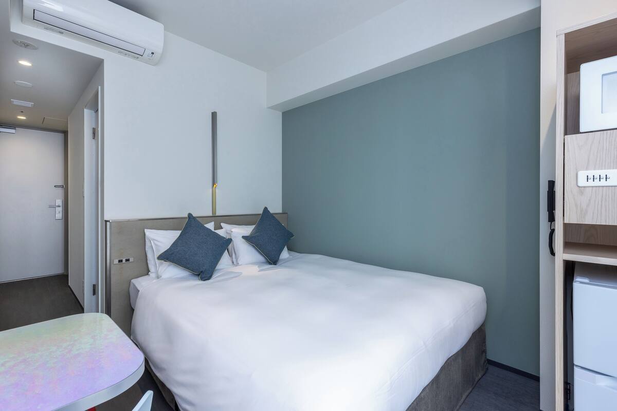 Ein Hotelzimmer mit Bett, Schreibtisch und Klimaanlage.
