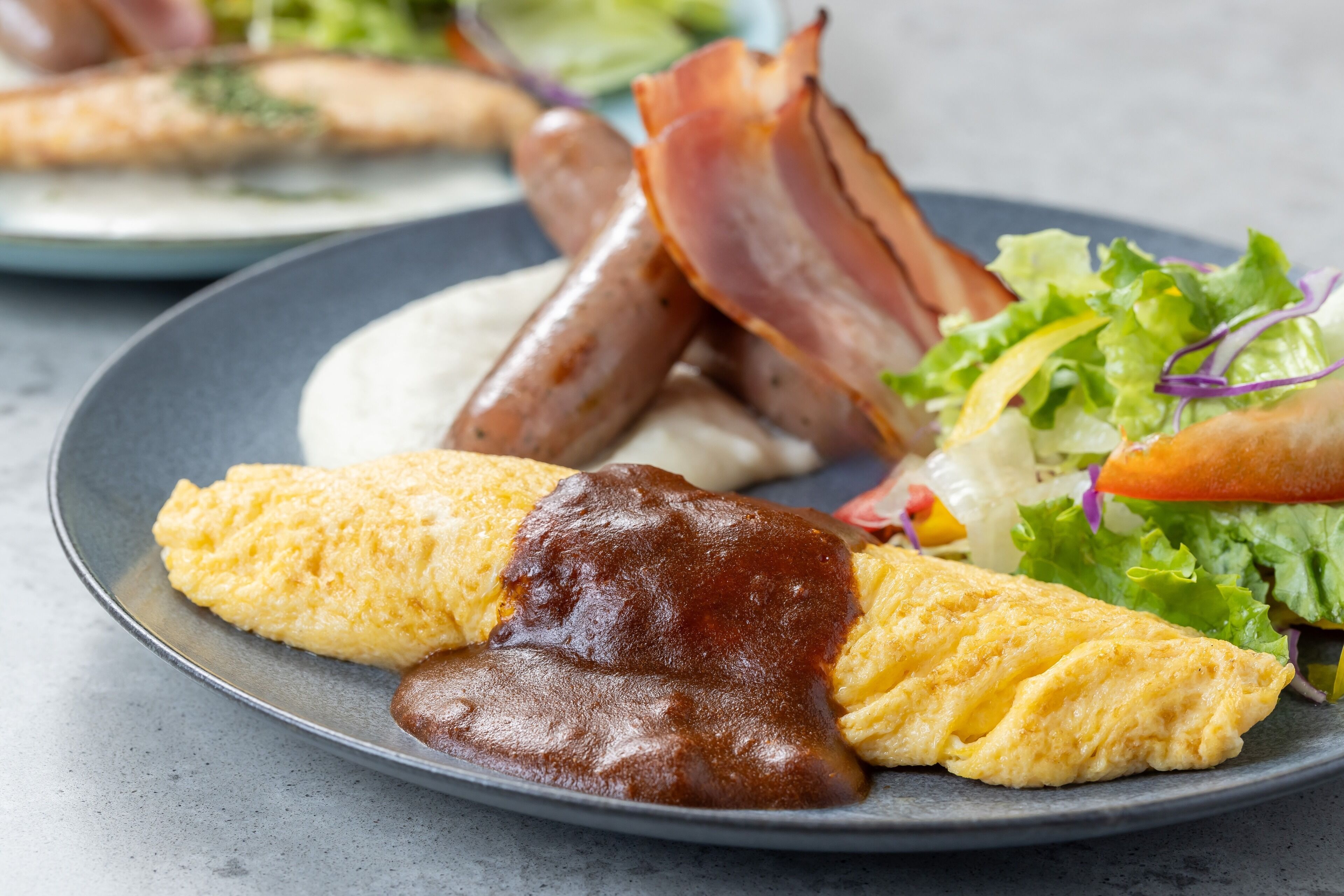 A plate with eggs, bacon, sausages, and a salad.