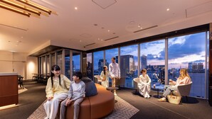 Un interior moderno con zona de estar, ventanas amplias y vista a la ciudad.