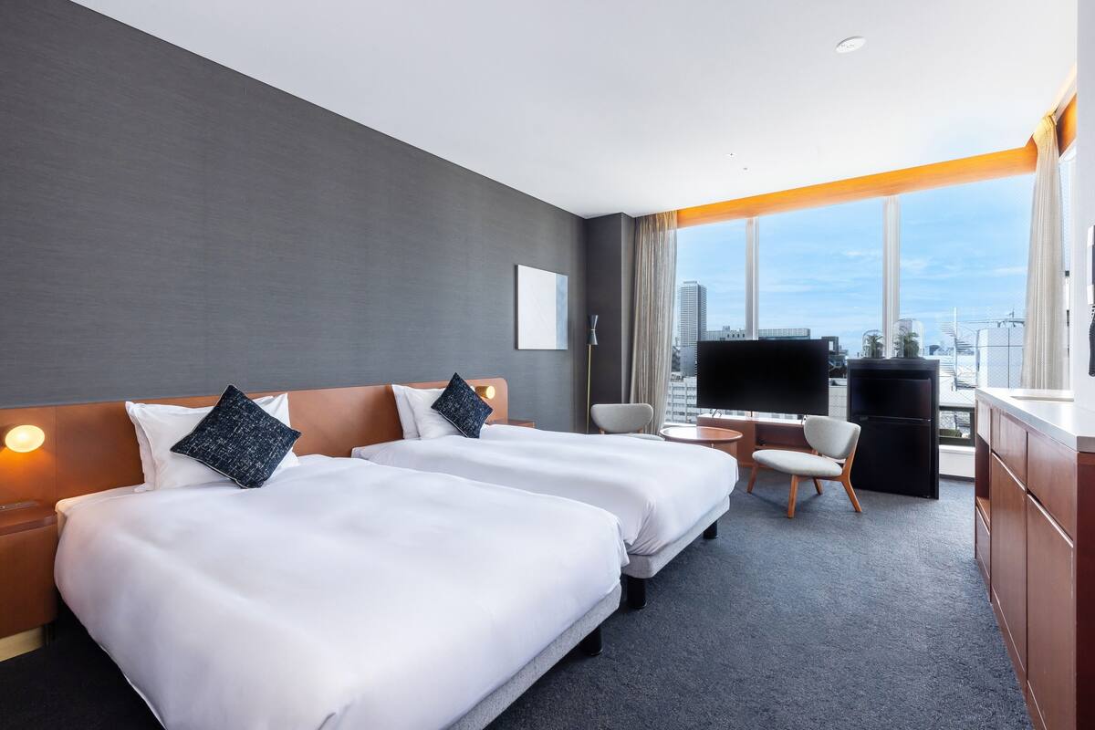 Ein Hotelzimmer mit zwei Betten, einem Schreibtisch, einem Stuhl und einem Fernseher.