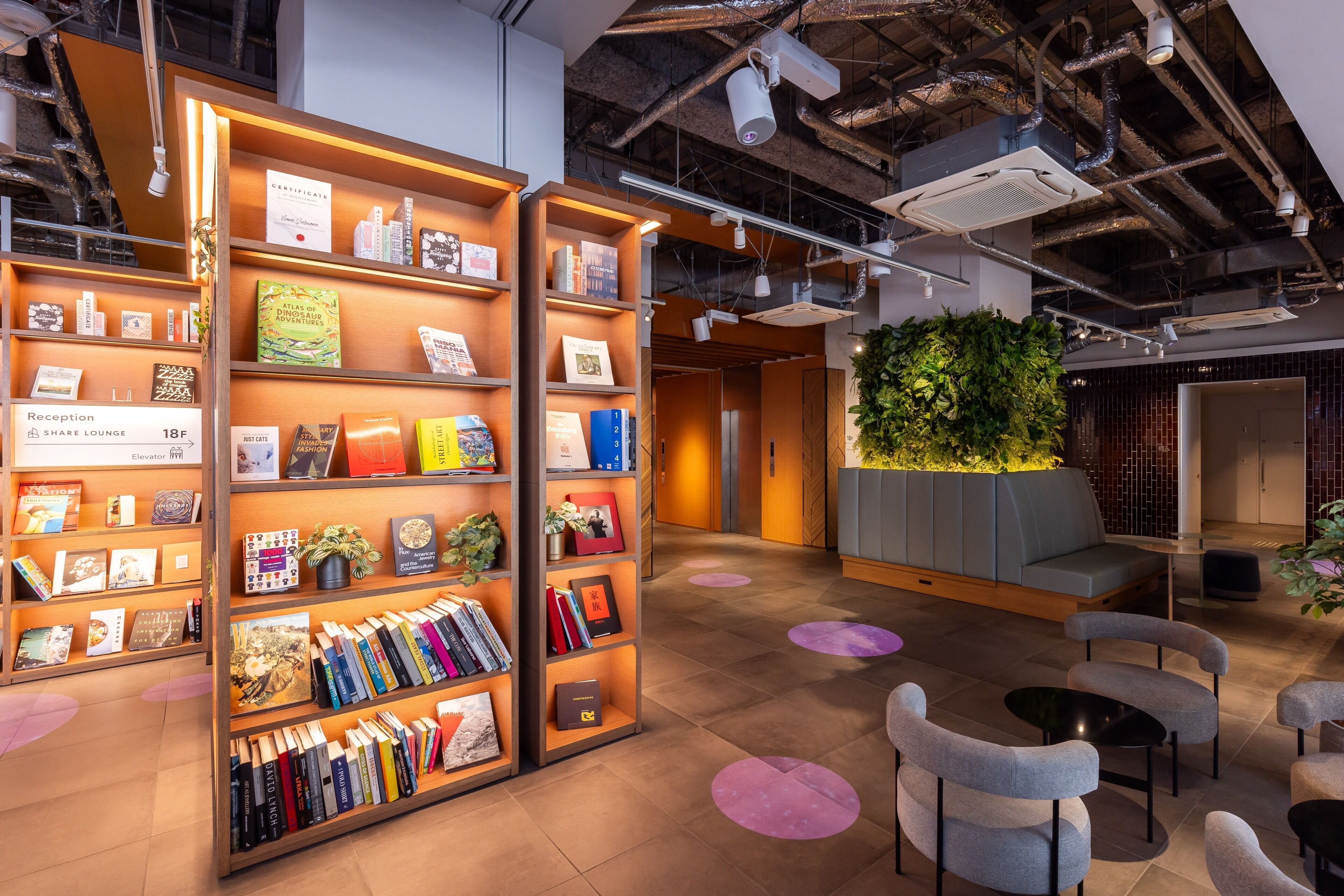 Ein Empfangsbereich mit Rezeption, einer Lounge mit Sitzgelegenheiten und einem Bücherregal.