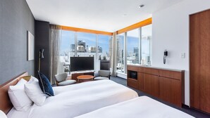 Una habitación de hotel moderna con una cama grande, televisión, escritorio y vistas a la ciudad.