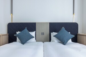 A double bed with two pillows, a headboard with a light switch, and bedside tables.