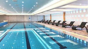 Ein Schwimmbecken mit mehreren Bahnen, Liegestühlen und einem Empfangsbereich.