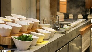 Ein reichhaltiges Buffet mit mehreren weißen Schalen, die auf einer Theke platziert sind und Speisen enthalten.