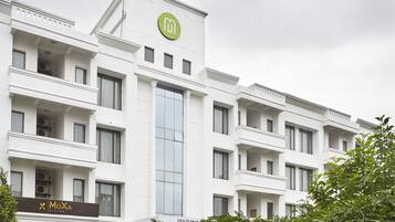 A modern white building with balconies, a green logo, and a MoXA Bistro sign.