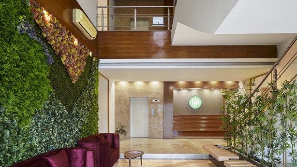 A modern lobby with a green wall, a staircase, and a reception desk.