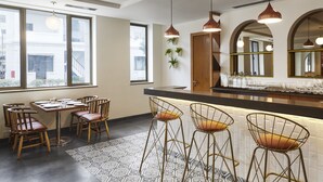 A modern bar area with high stools, a long counter, and pendant lighting.