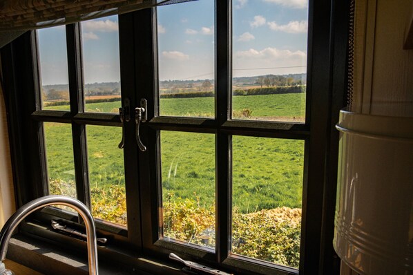 Una ventana con vista a un campo verde y un paisaje distante.