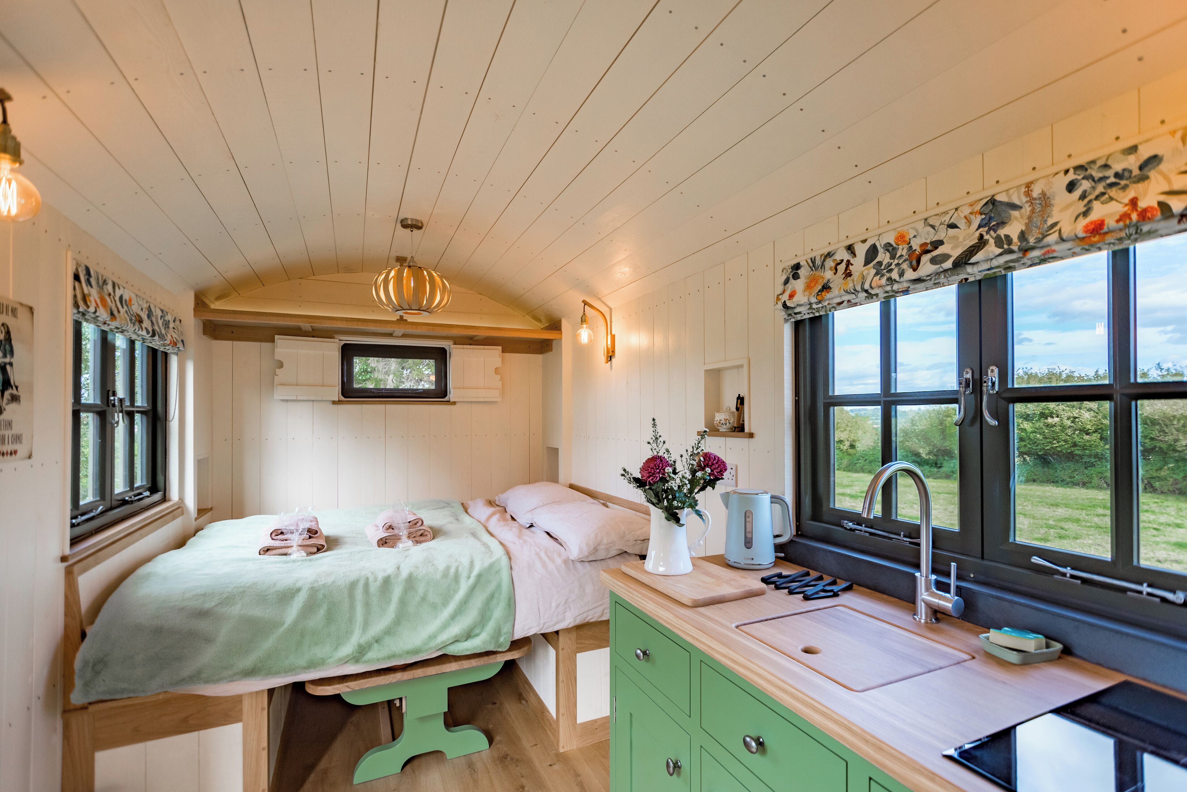 Ein gemütliches Schlafzimmer mit Bett, Nachttisch und Fenster mit Blick auf Grünflächen.