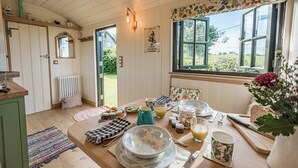A cozy breakfast setup with a wooden table, breakfast items, and a view of the garden through a window.