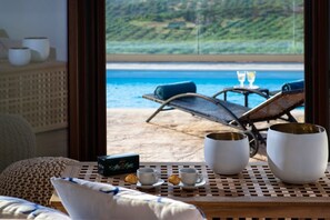 A room with a view of the beach, a table with cups and a box of tea, and a chair by the window. - Villa Liatiko, Heated pool, Amazing views (Hersonissos)