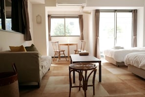 A hotel room with a bed, a sofa, a dining table with chairs, and a window with curtains.