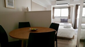 A hotel room with a round wooden table, two chairs, a bed with white linens, a window with curtains, and a framed picture on the wall. - Tokyo Sakurako Hatchobori (Tokyo)