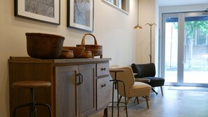 A kitchen with a wooden cabinet, wicker baskets, a bar stool, and a chair. - Tokyo Sakurako Hatchobori (Tokyo)