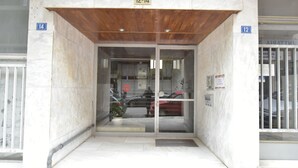 A building entrance with a wooden ceiling, numbered doors, and a glass door. - Live As A Greek in Artemis Apartment (Athens)
