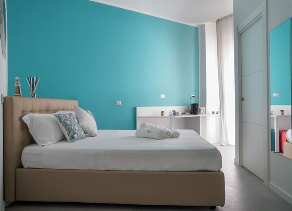 A bedroom with a bed, a nightstand, and a desk with a lamp. - Dimora Chloe (Pescara)