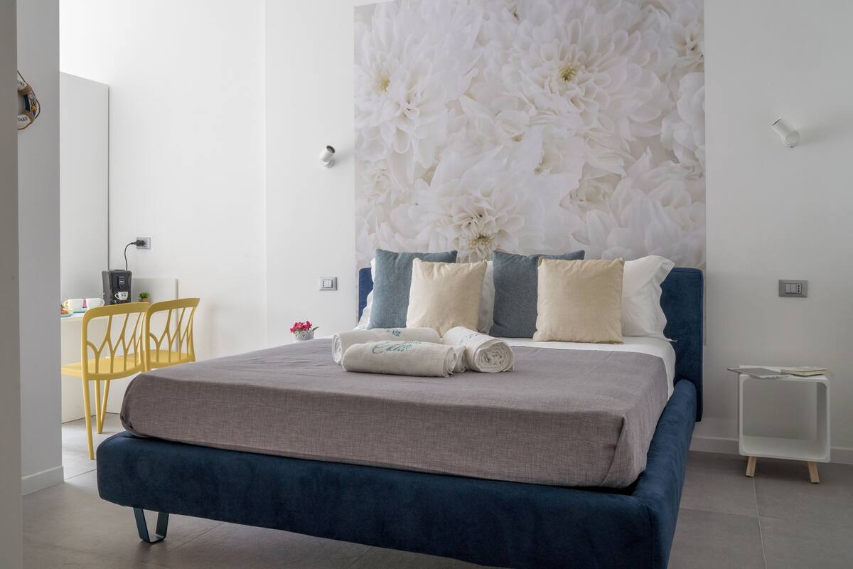 Un dormitorio moderno con una cama grande, un escritorio con silla y una pared con estampado floral.