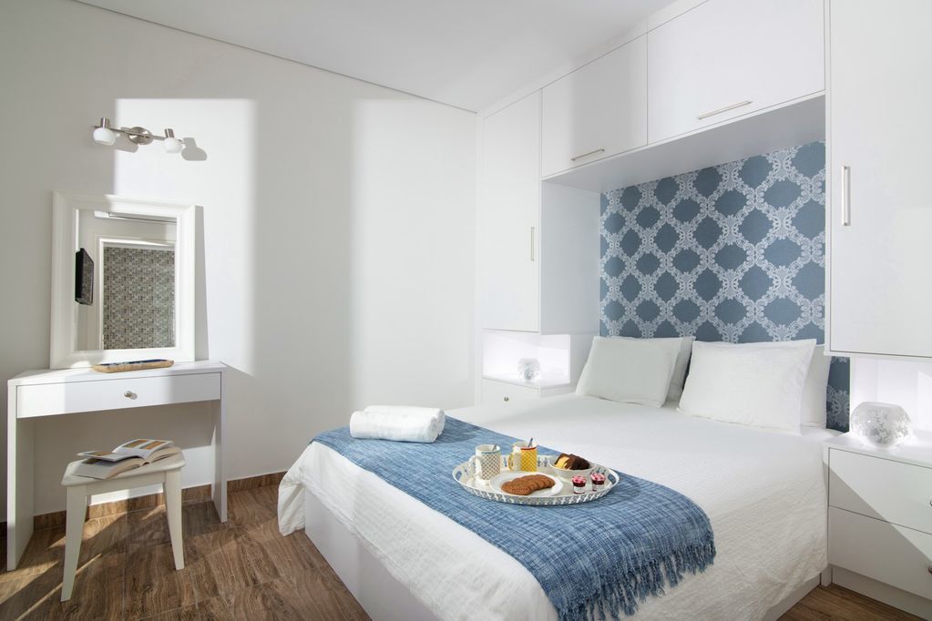 A hotel room with a bed, a desk, and a dresser.