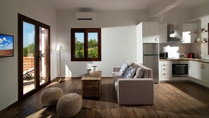 A modern living room with a sofa, ottomans, a coffee table, and a view of the outdoors through large windows.