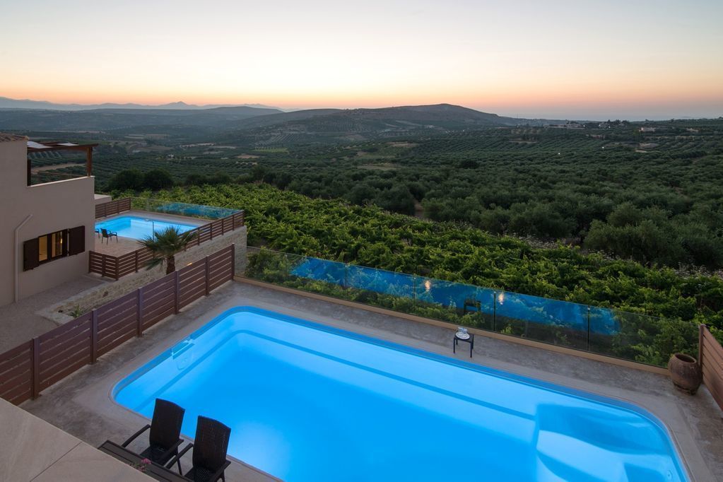 A swimming pool with a view of vineyards and distant hills.
