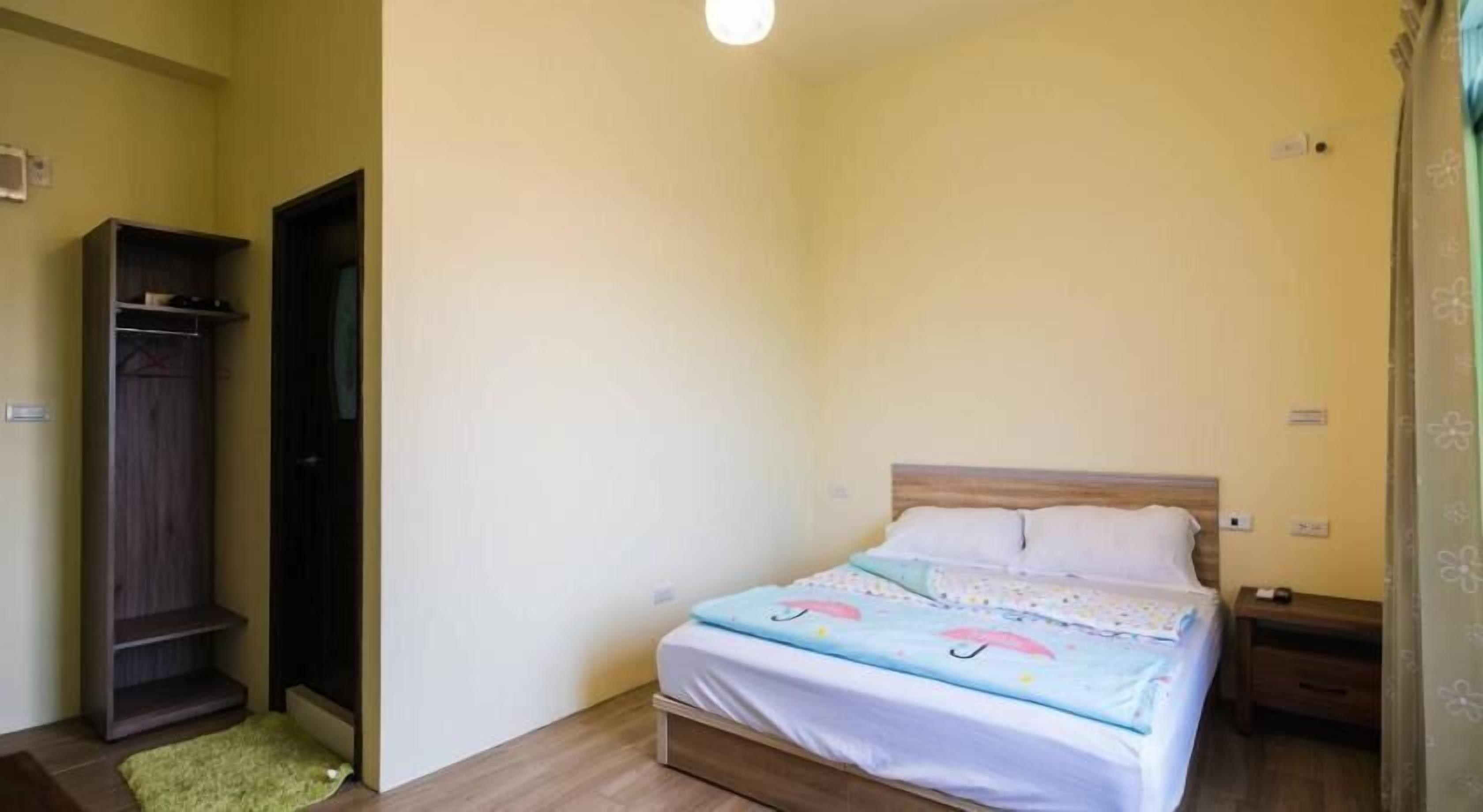 A bedroom with a bed, a wardrobe, and a nightstand.