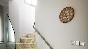 Eine Treppe mit Marmorstufen, einem Glasgeländer und einer an der Wand montierten Uhr.