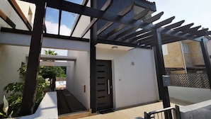 Ein überdachter Außenbereich mit einer Pergola, einer Tür und einer Treppe, die zu einem Eingang führt.