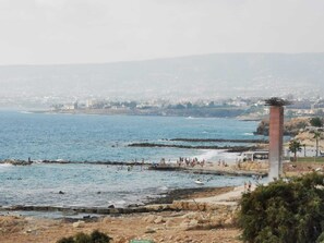 A coastal area with a rocky beach, a pier, and a cityscape in the background. - Sea side holiday villa, perfect location, maximum relaxation. (Chlorakas)