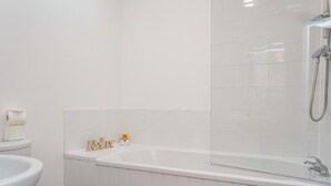 A bathroom with a white bathtub, a toilet, and a sink. - Cherry Property - Apple Suite (Blackpool)