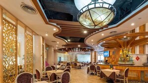 Un restaurant spacieux avec de hauts plafonds, un éclairage moderne et un bar central.