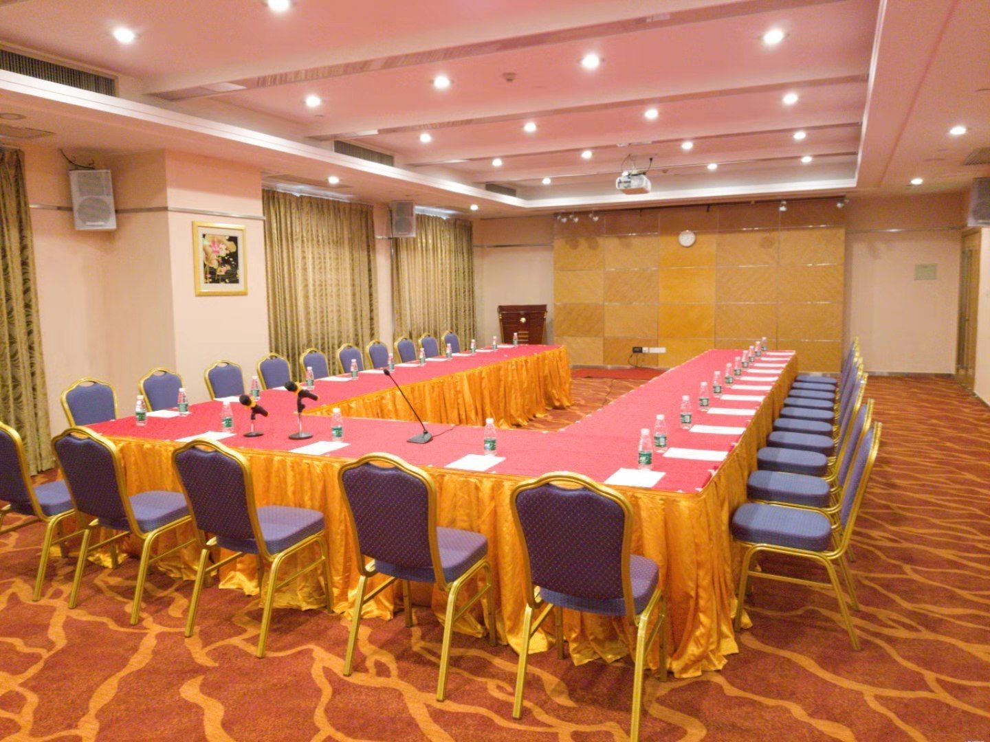 Un salón de conferencias con una larga mesa, sillas y una pantalla para proyector.