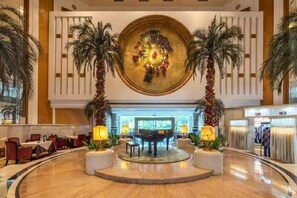 A lobby with a central circular artwork, palm trees, and a seating area with tables and chairs. - Panyu Guest House (Guangzhou)