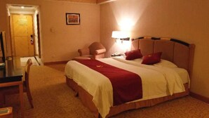 Une chambre d’hôtel avec un grand lit, un bureau et une chaise.
