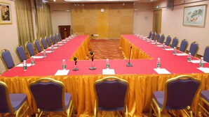 Une salle de conférence équipée d’une longue table, de chaises, de microphones et de bouteilles d’eau.