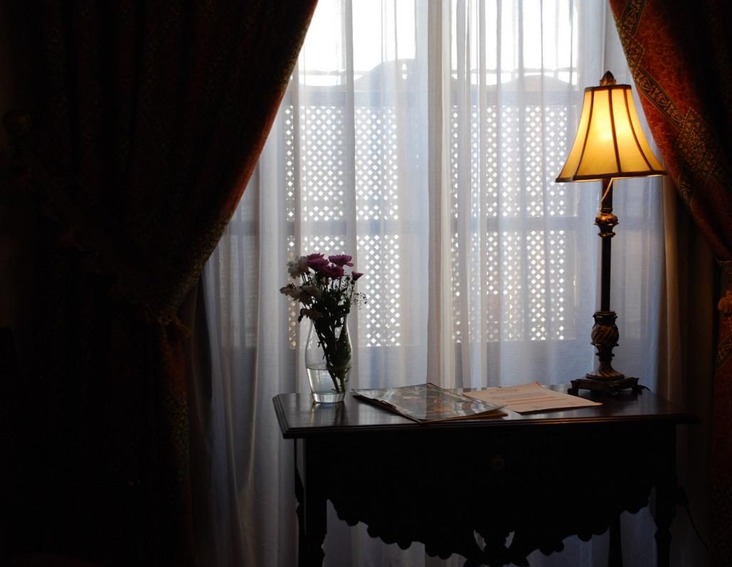 Une table avec une lampe, un vase de fleurs et des papiers.